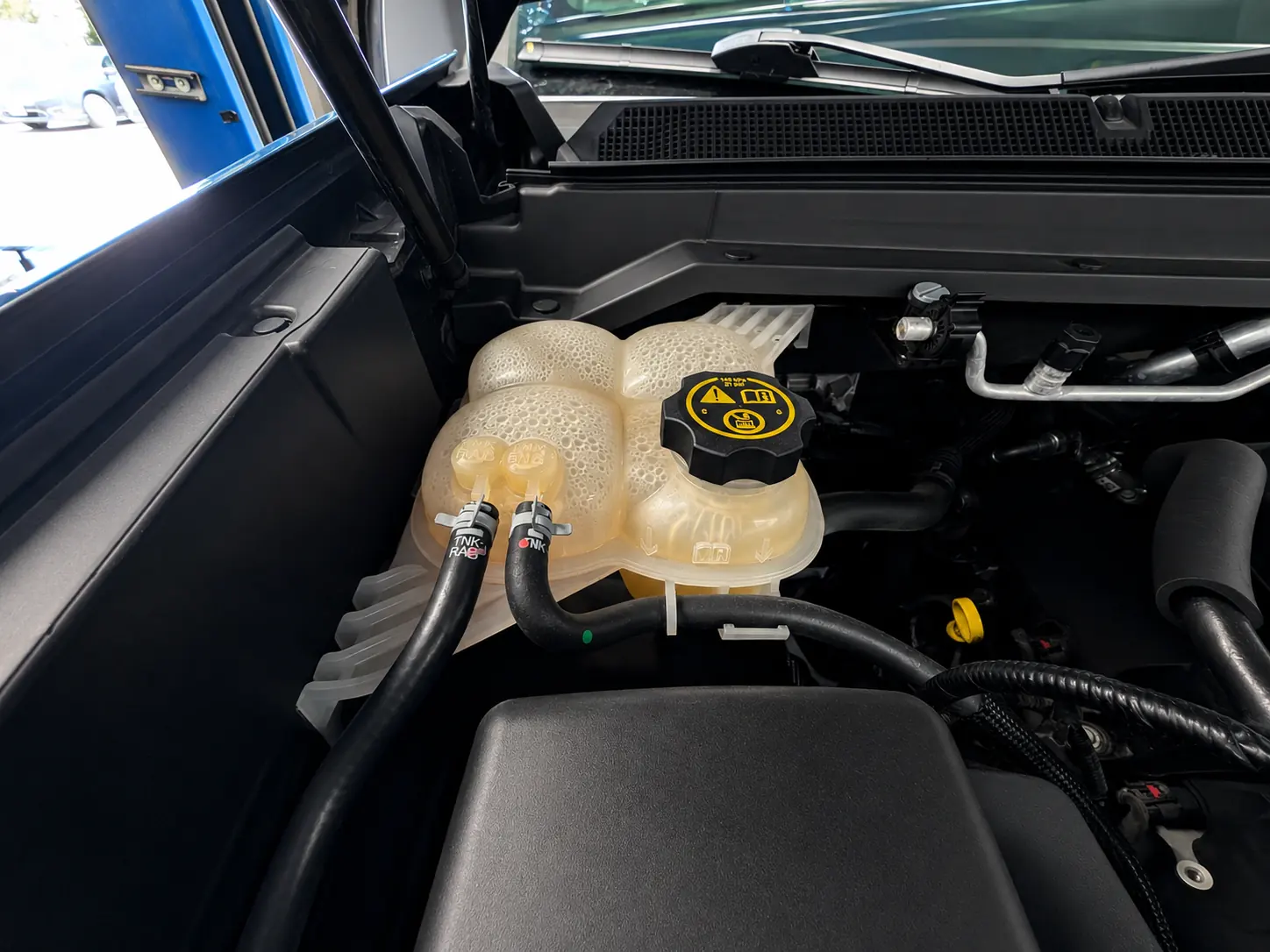 Coolant reservoir and cooling system components under the hood