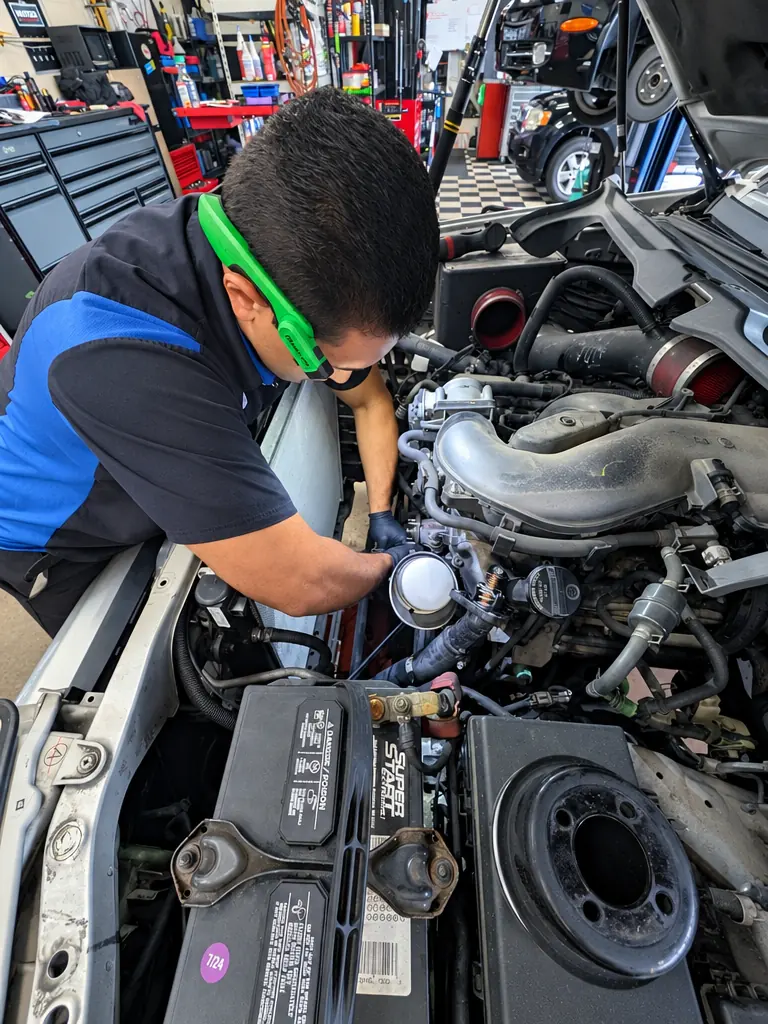 HB Auto & AC technician working under the hood of a vehicle